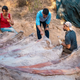 Three workers stand over the massive ribs of a sauropod dinosaur.